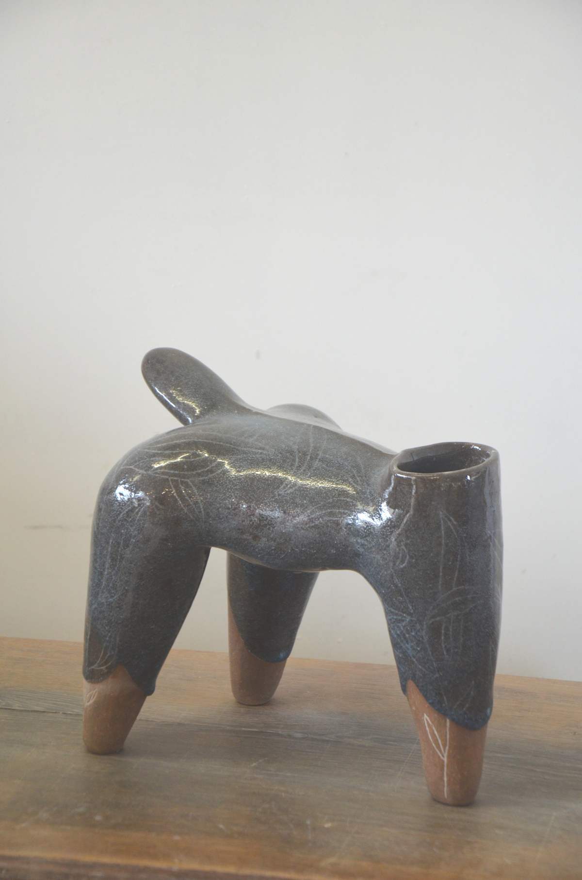 Pièce grise et brillante à quatre pieds bruns, posée sur une table en bois.